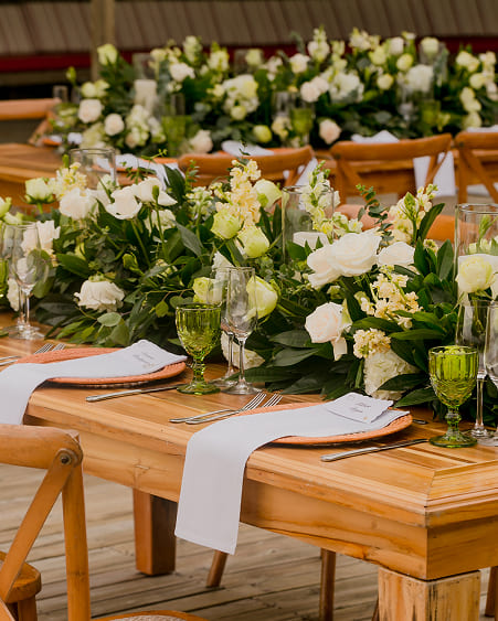 Montaje de mesa de boda con centros de mesa florales sobre madera natural