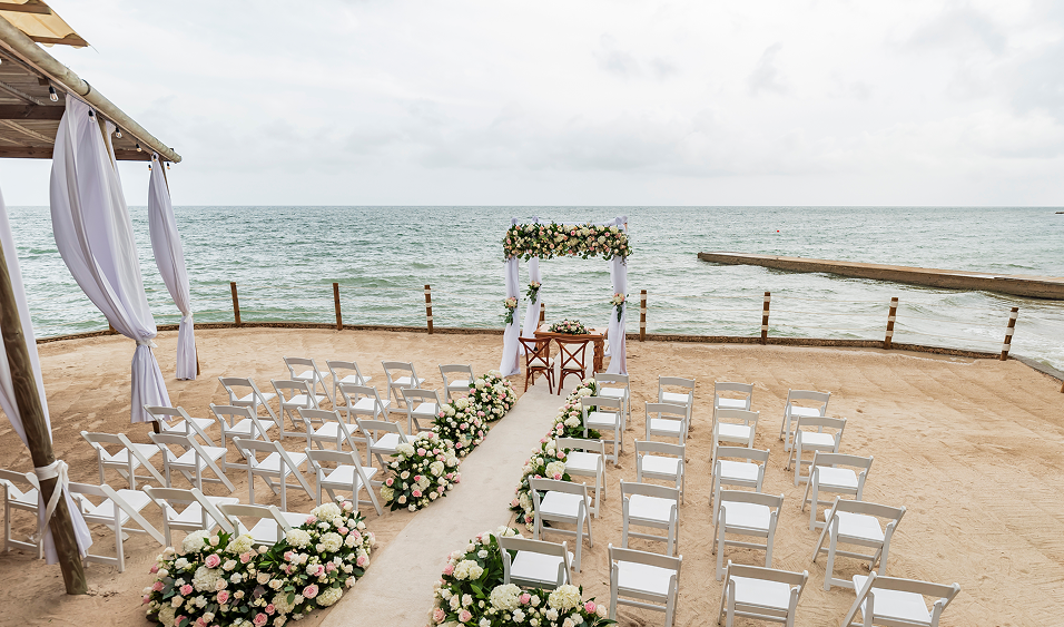 Ceremonia de boda frente al mar con montaje en playa y decoración floral en Isla del Encanto